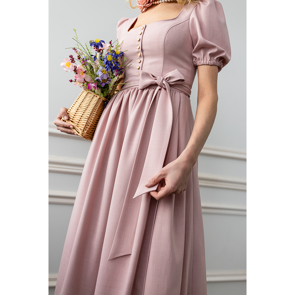 Verspieltes Dirndl in Flamingo-Rosa mit Puffärmeln, geradem Ausschnitt und Knopfleiste. Die passende Schürze ist mit einer Schleife gebunden, das Modell reicht bis knapp über das Knie.