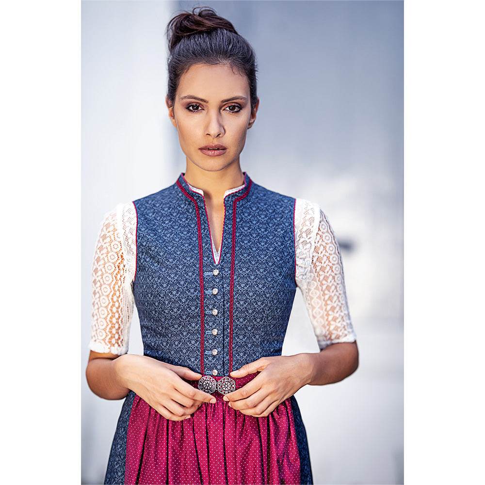 Klassisches Dirndl mit dezentem Muster, V-Ausschnitt mit schlanker Borte und kurzem Stehkragen, Knopfleiste mit herzförmigen Knöpfen sowie Schürze mit Schließe in Blau und Bordeaux.