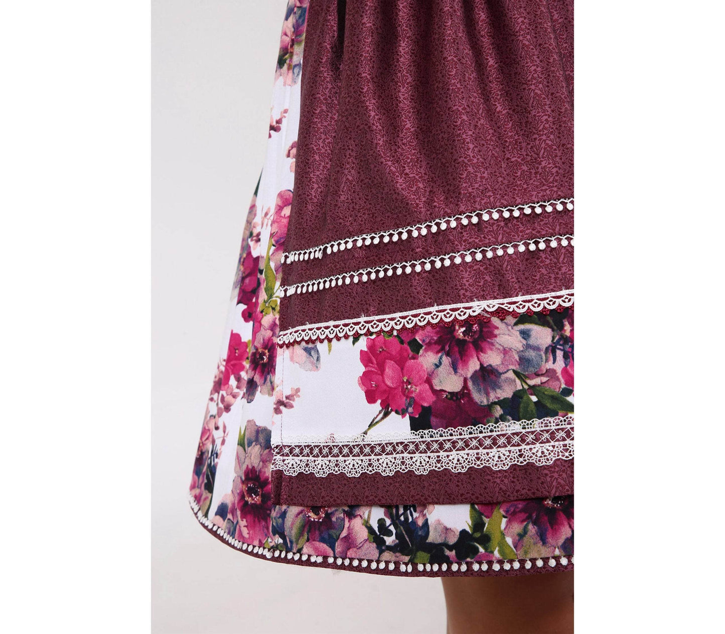 Pinkes Dirndl mit herzförmigem Mieder, mittigem Reißverschluss und floralem Muster, dazu passende Schürze mit gleichen Blumenmotiven, romantisch und frühlingshaft.