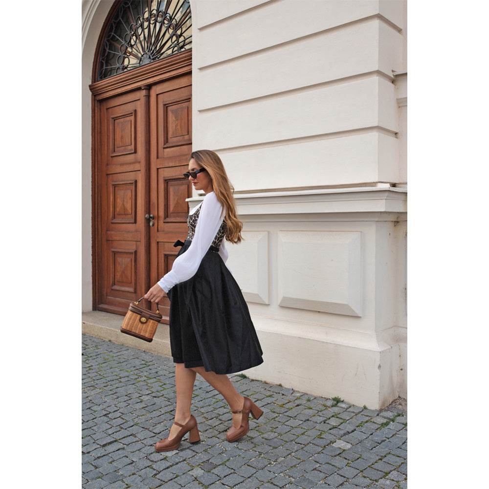 Elegantes Dirndl in Schwarz mit auffälligem Leoprint-Mieder und schlichtem schwarzen Rock. Das Mieder zeigt ein Tigerlook-Muster mit Reißverschluss, die Schürze ist unifarben. Das zweilagige Dirndl wirkt modern und zieht durch das Muster alle Blicke auf sich.
