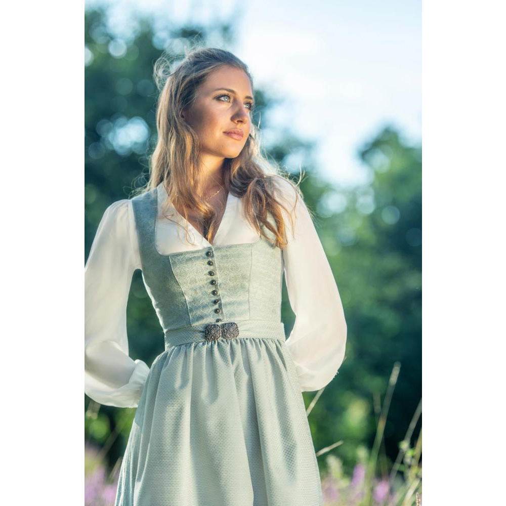Dirndlbluse in Off-White mit langen, voluminösen Puffärmeln aus transparentem Chiffon, V-Ausschnitt und durchgehender Knopfleiste. Die Ärmel enden in breiten, geknöpften Manschetten mit feinen Details.