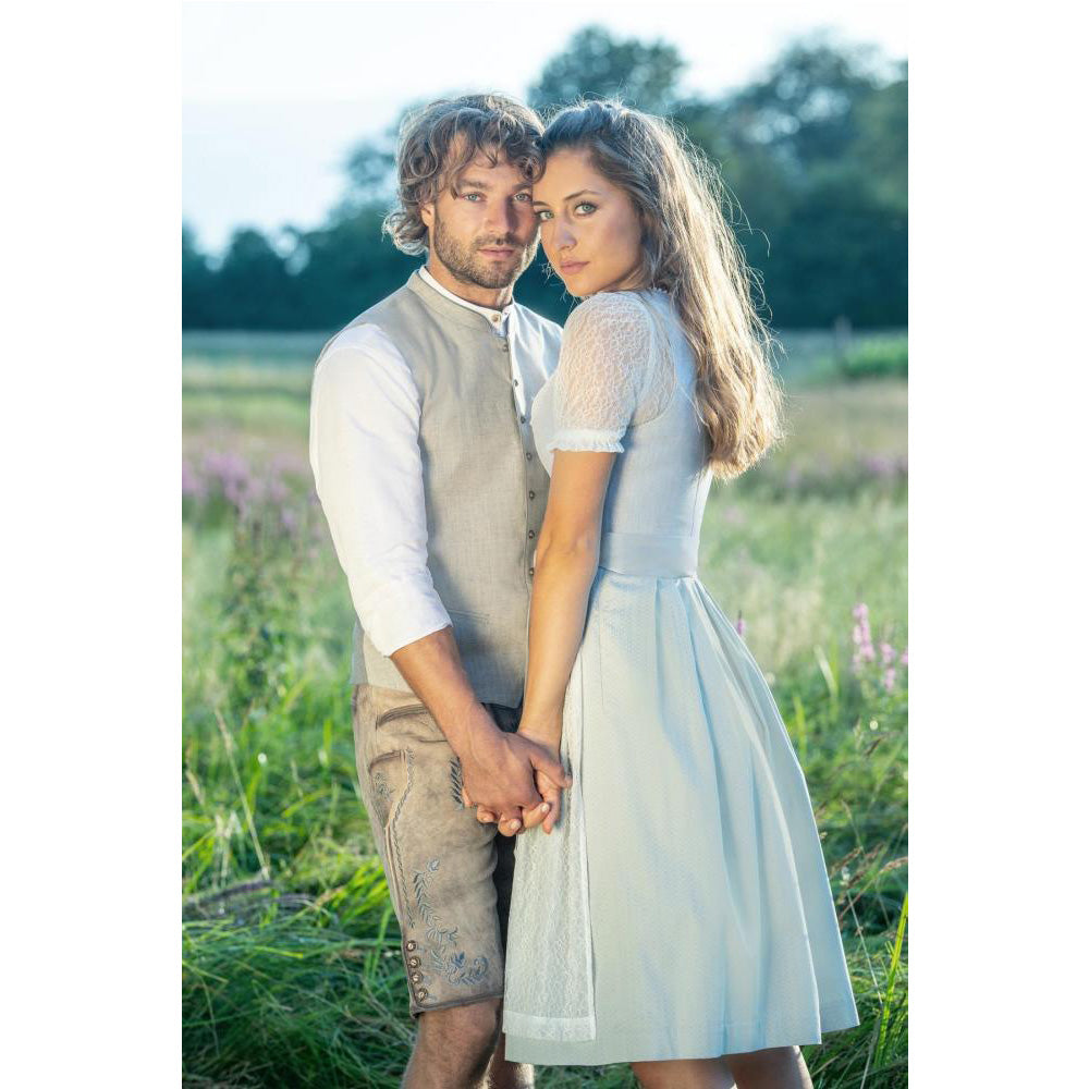 Kurze Trachtenlederhose in Steingrau/Denim mit rundem Latz, floralen Stickereien und rustikalem Used-Look – modern interpretiert im traditionellen Stil.