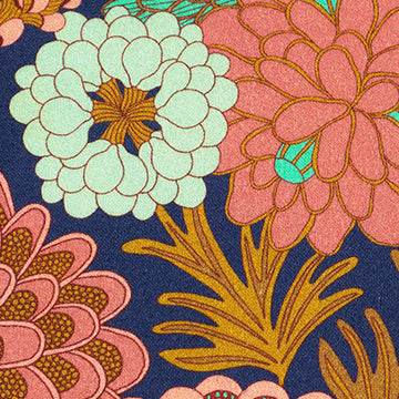 Stoffkombination mit einfarbigem apricotfarbenem Baumwollstoff für Oberteil und Rock sowie dunkelblauer Schürze mit buntem Blumenmuster.