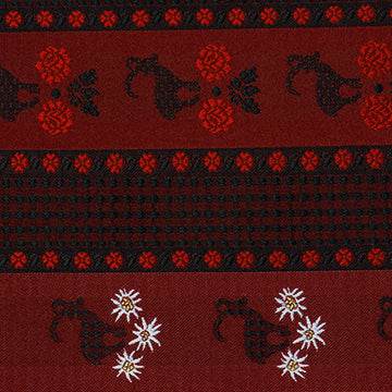 Schwarzer Baumwollsatin für Oberteil und Rock, dazu eine Schürze mit Muster aus Steinbock und Blümchen in Rot, Schwarz, Weiß und Gelb.