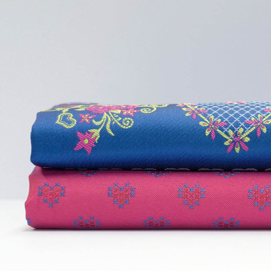 Trachtenstoff mit Herzchenmuster in Fuchsia, Rot und Blau für Oberteil und Rock, dazu eine Schürze mit Blumenbordüre in Royalblau, Rosé, Fuchsia und Hellgrün.