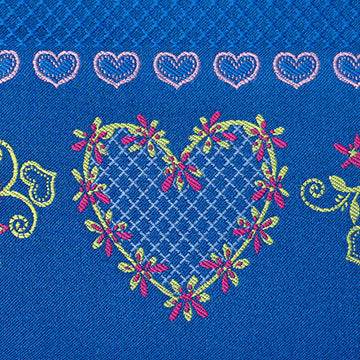 Trachtenstoff mit Herzchenmuster in Fuchsia, Rot und Blau für Oberteil und Rock, dazu eine Schürze mit Blumenbordüre in Royalblau, Rosé, Fuchsia und Hellgrün.