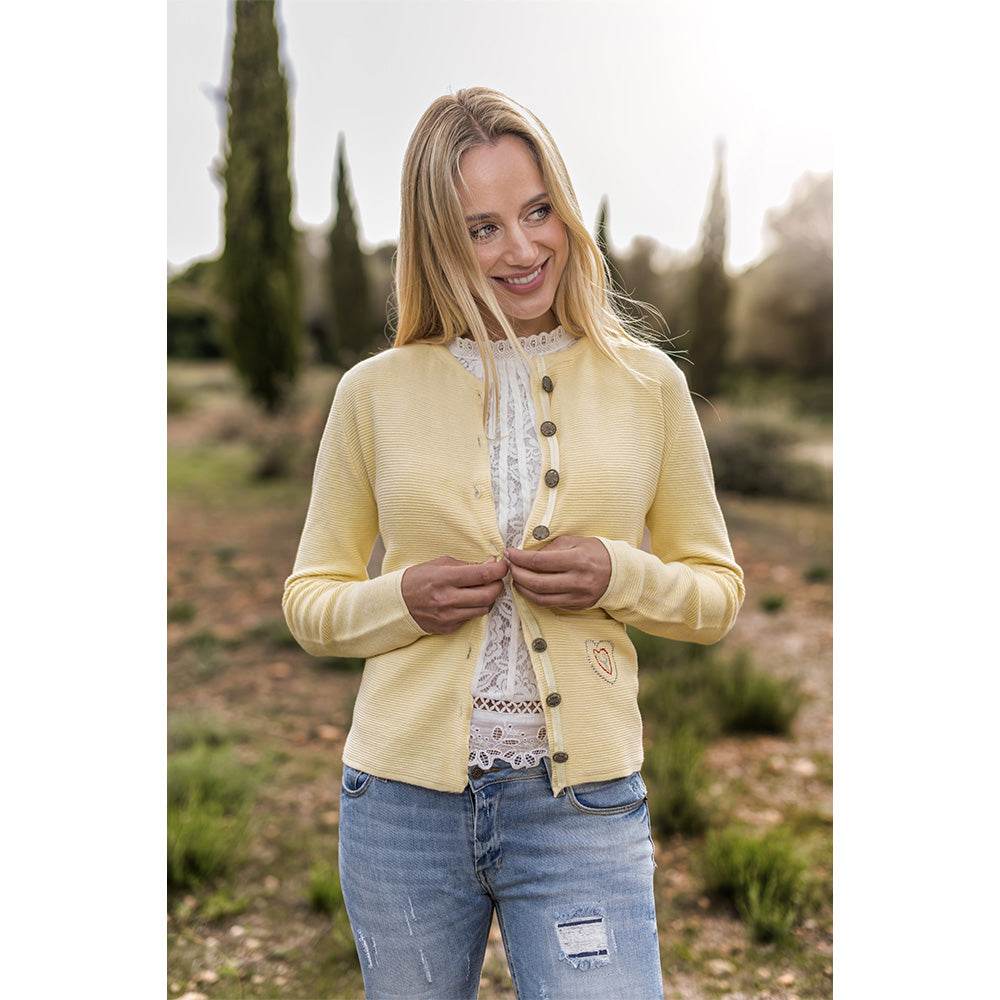 Gelbe Trachten-Strickjacke mit Rippstruktur, Edelweiß-Knöpfen und Strassverzierung an der Eingriffstasche, locker geschnitten und modisch gestaltet.