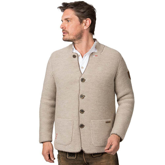 Strickjacke in hellem Sandton mit Stehkragen, aufgesetzten Taschen und rustikalen Hornknöpfen, im Sakko-Stil geschnitten, getragen als moderner Trachtenlook.