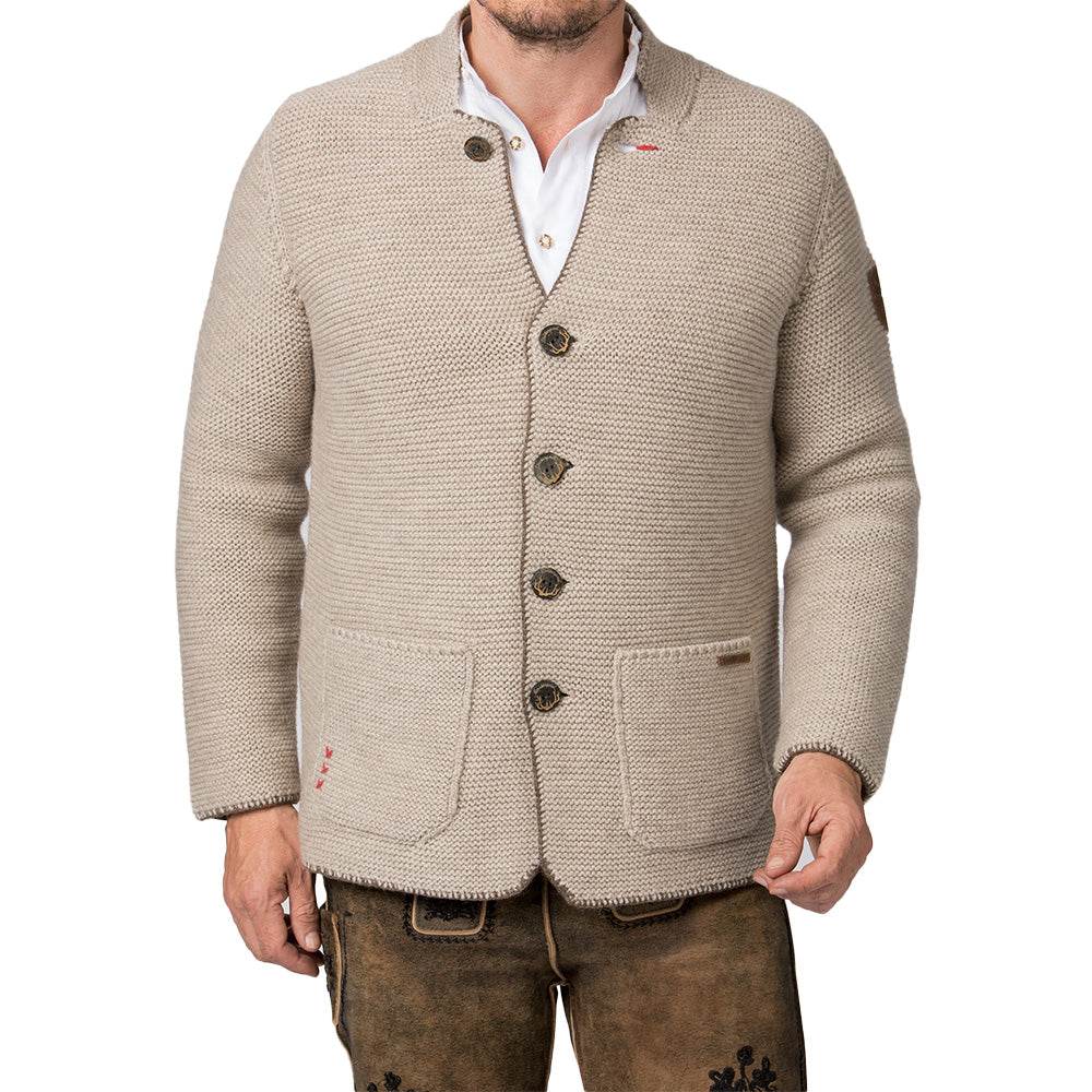Strickjacke in hellem Sandton mit Stehkragen, aufgesetzten Taschen und rustikalen Hornknöpfen, im Sakko-Stil geschnitten, getragen als moderner Trachtenlook.