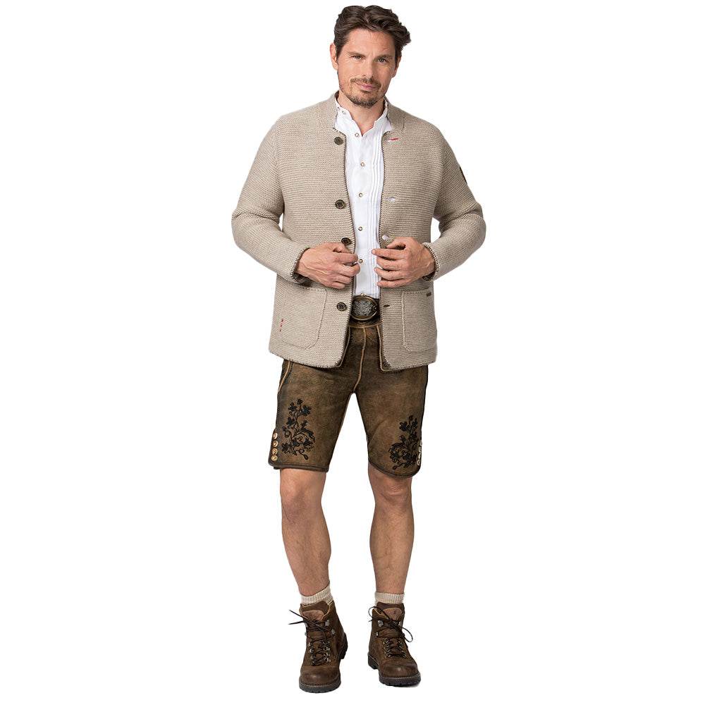 Strickjacke in hellem Sandton mit Stehkragen, aufgesetzten Taschen und rustikalen Hornknöpfen, im Sakko-Stil geschnitten, getragen als moderner Trachtenlook.