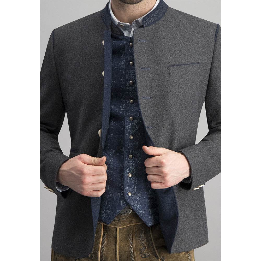 Trachtenjacke aus meliertem Stoff in dunkelgrau-blau mit geradem Schnitt, besticktem Stehkragen, Pattentaschen und Hornknöpfen, hinten mit Kellerfalte und Knopfriegel, im traditionellen, lässigen Stil.