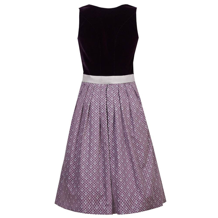 Elegantes Dirndl mit schlichtem Samtmieder in pflaumenfarbe und Reißverschluss mit Herzanhänger. Der Rock ist zart gepunktet, die mauvefarbene Schürze wird durch eine dekorative Schließe ergänzt.