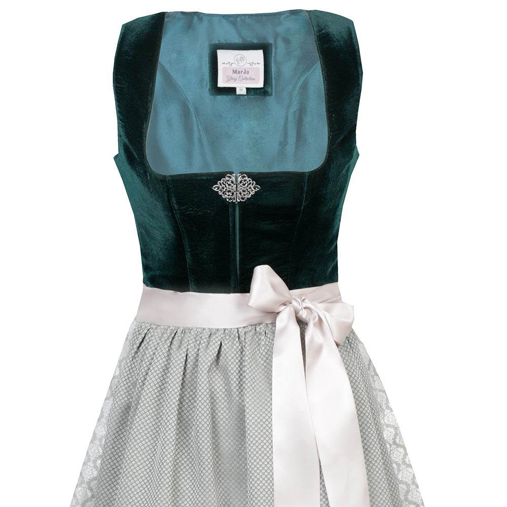Elegantes Dirndl mit schlichtem Samtmieder in smaragdgrün und Reißverschluss sowie Schließe am Ausschnitt. Der Rock zeigt ein Ornamentenmuster und ist farblich abgestimmt mit der passenden Schürze.