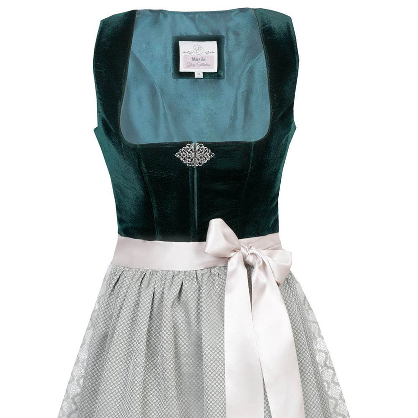 Elegantes Dirndl mit schlichtem Samtmieder in smaragdgrün und Reißverschluss sowie Schließe am Ausschnitt. Der Rock zeigt ein Ornamentenmuster und ist farblich abgestimmt mit der passenden Schürze.