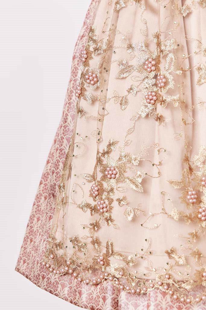 Bezauberndes Dirndl mit herzförmigem Mieder, mittigem Reißverschluss und passender Schnürung. Das Kleid zeigt ein einheitliches Muster in Rosé- und Beigetönen. Die Schürze besteht aus feiner Spitze mit Perlen und einem kontrastierenden Unterstoff. Ein elegantes und edles Dirndl, das auch als Hochzeitsdirndl geeignet ist.