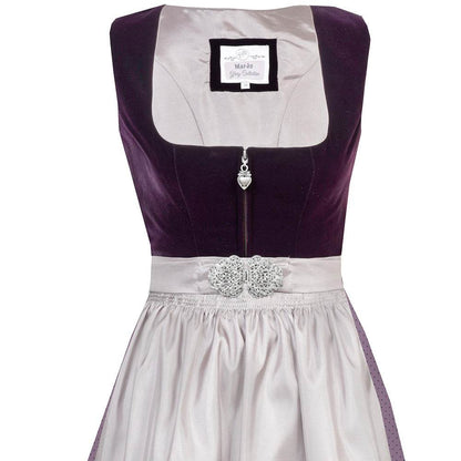 Elegantes Dirndl mit schlichtem Samtmieder in pflaumenfarbe und Reißverschluss mit Herzanhänger. Der Rock ist zart gepunktet, die mauvefarbene Schürze wird durch eine dekorative Schließe ergänzt.