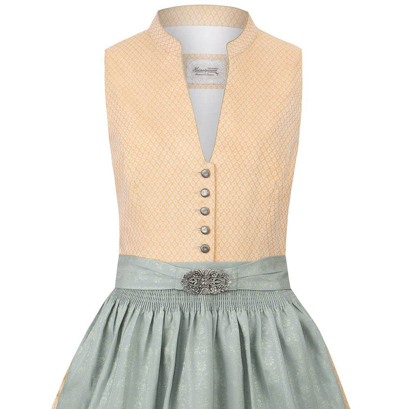 Klassisches gelbes Dirndl mit hochgeschlossenem Schnitt, V-Ausschnitt mit dekorativen Knöpfen, fein gemustertem Stoff und unifarbener Schürze mit Metallschließe.