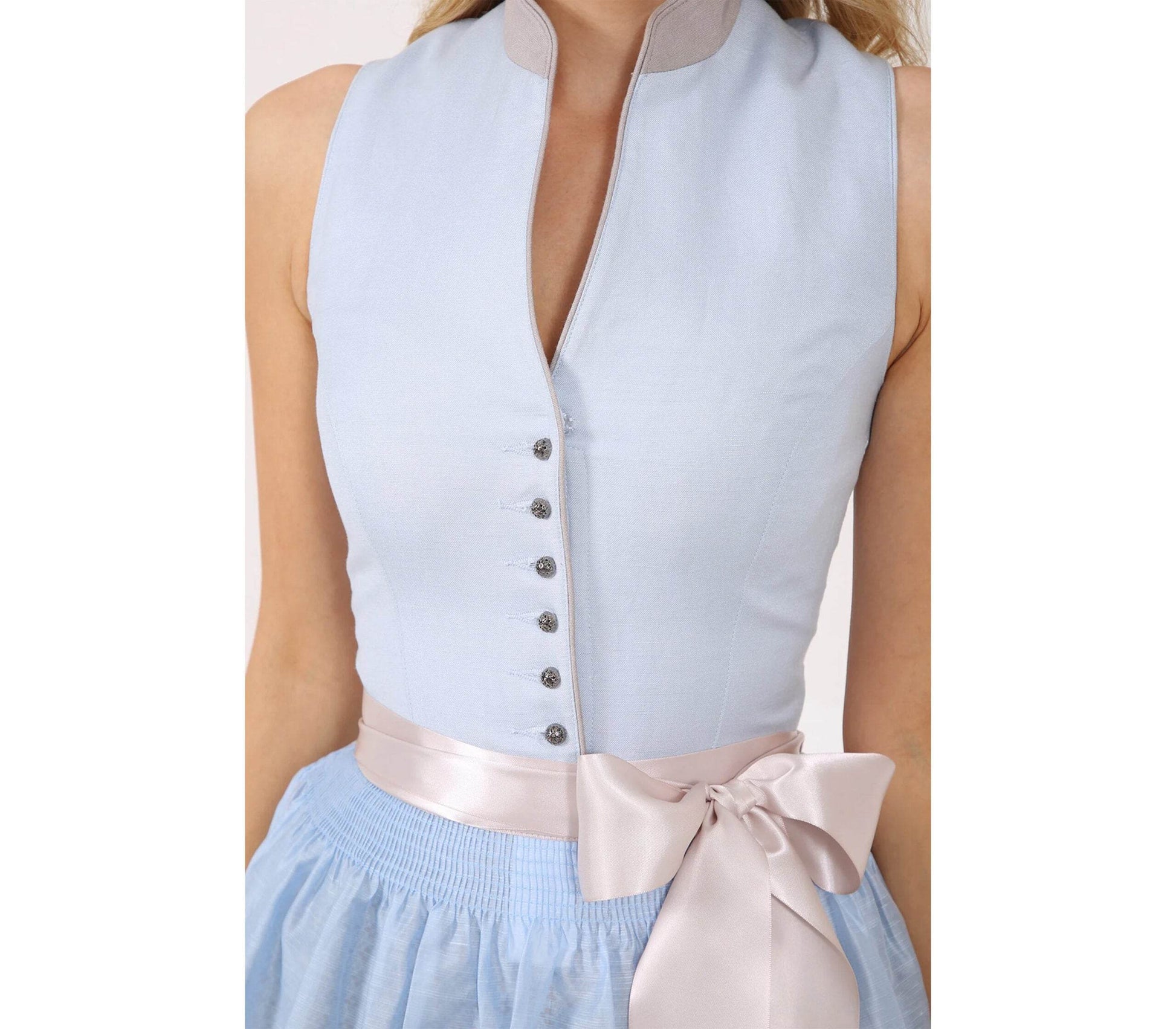 Klassisches Dirndl mit dezentem Muster am Rock, hochwertigen Knöpfen am Mieder, farblich abgestimmter Schürze und kurzem Stehkragen am Ausschnitt.
