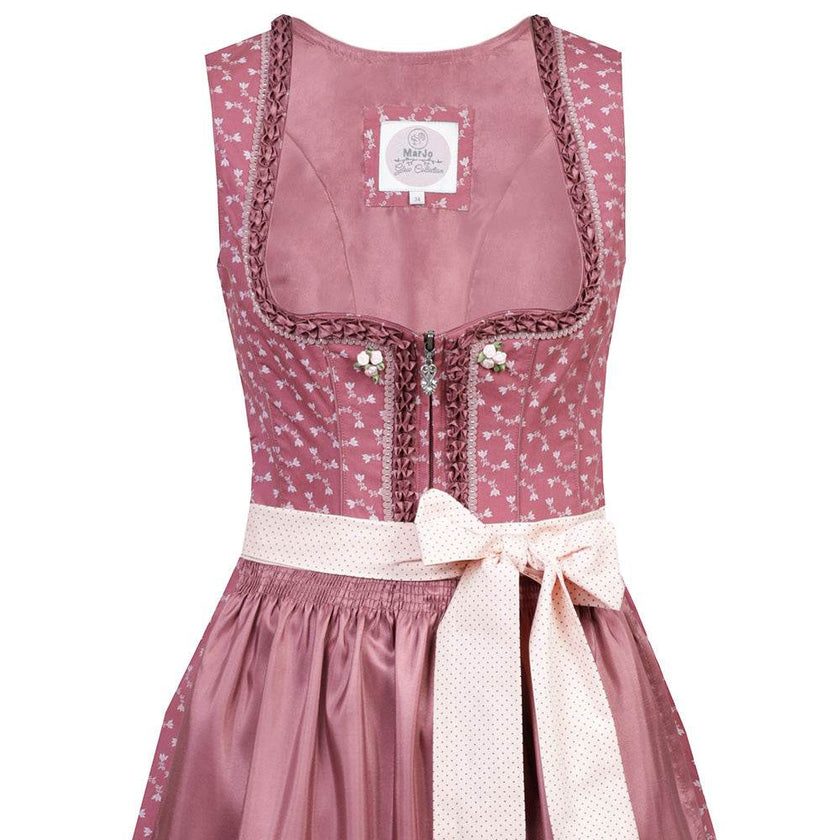 Nettes Dirndl in canberry-Farbe mit liebevollem Blumenmuster, Satinschürze mit Musterwiederholung und einem dekorativen Schleifenband. Das Mieder zeigt einen Reißverschluss, der Ausschnitt ist aufwendig verziert.
