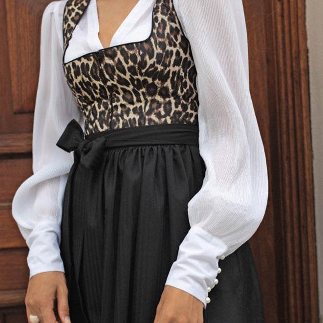 Elegantes Dirndl in Schwarz mit auffälligem Leoprint-Mieder und schlichtem schwarzen Rock. Das Mieder zeigt ein Tigerlook-Muster mit Reißverschluss, die Schürze ist unifarben. Das zweilagige Dirndl wirkt modern und zieht durch das Muster alle Blicke auf sich.