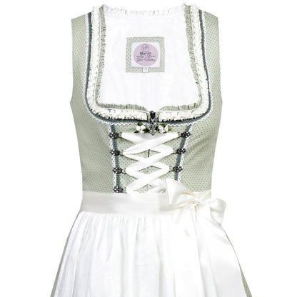Liebreizendes Dirndl in zartem Salbei mit doppellagiger Schürze aus Spitze und Taft, verziert mit feinen Details. Das Mieder zeigt Reißverschluss und Schnürung, der Ausschnitt ist kunstvoll geschmückt.