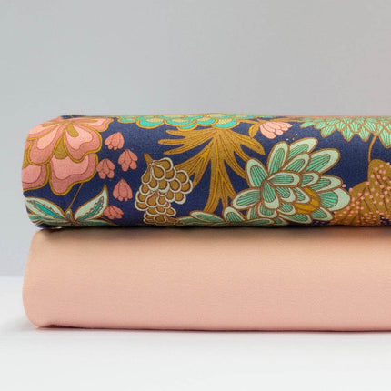 Stoffkombination mit einfarbigem apricotfarbenem Baumwollstoff für Oberteil und Rock sowie dunkelblauer Schürze mit buntem Blumenmuster.