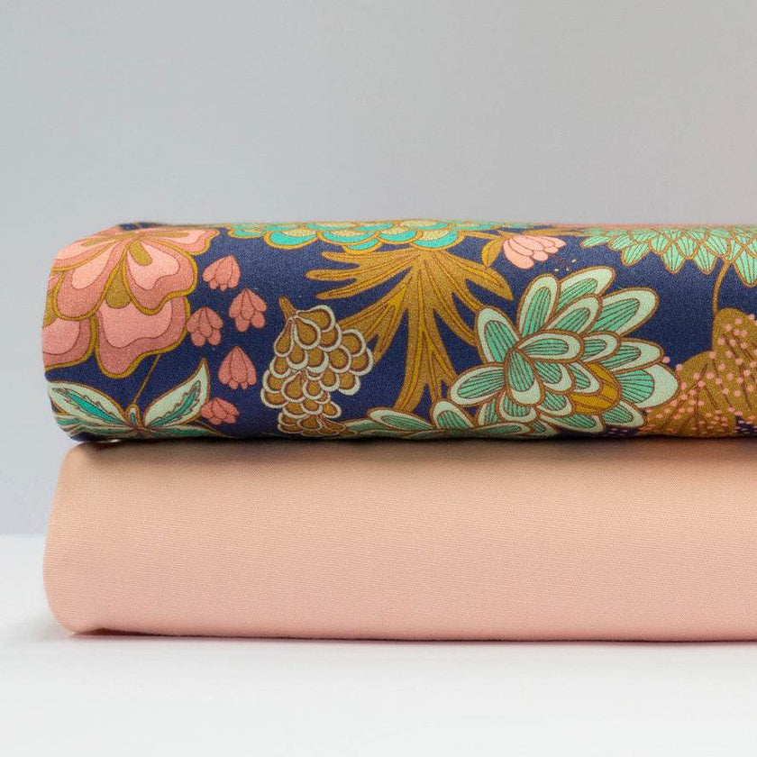 Stoffkombination mit einfarbigem apricotfarbenem Baumwollstoff für Oberteil und Rock sowie dunkelblauer Schürze mit buntem Blumenmuster.