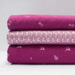 Stoffmuster für Dirndl mit Trachtenstoff in Fuchsia und Weiß mit kleinen Hirschen und Blumen für Erwachsene, kindliches Blümchenmuster in Pink und Grün sowie Schürze mit mehrfarbigem Blümchenjacquard in Weiß, Fuchsia, Blau und Lila.
