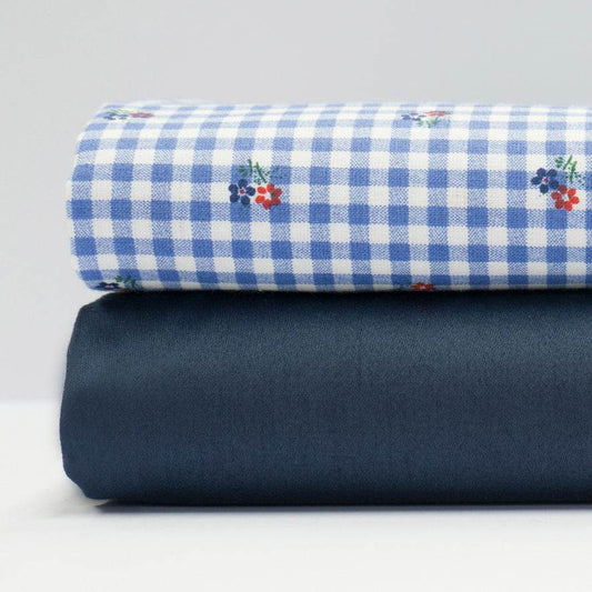 Stoffmuster für Dirndl mit marineblauem Baumwollsatin für Oberteil und Rock, dazu karierte Schürze mit buntem Blümchenmuster in Hellblau, Weiß, Rot und Grün.