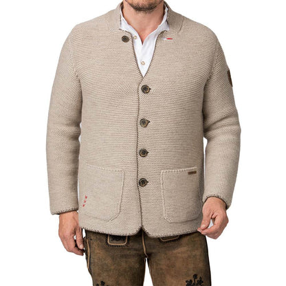 Strickjacke in hellem Sandton mit Stehkragen, aufgesetzten Taschen und rustikalen Hornknöpfen, im Sakko-Stil geschnitten, getragen als moderner Trachtenlook.